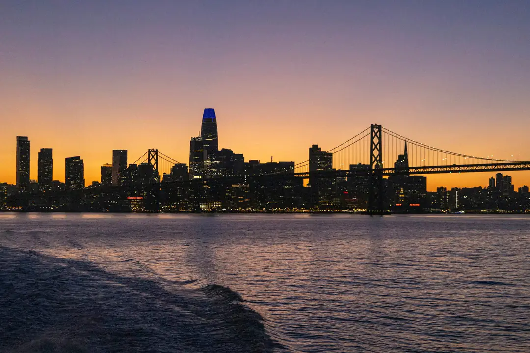The San Francisco skyline and Bay Bridge silhouetted against an amber dusk sky