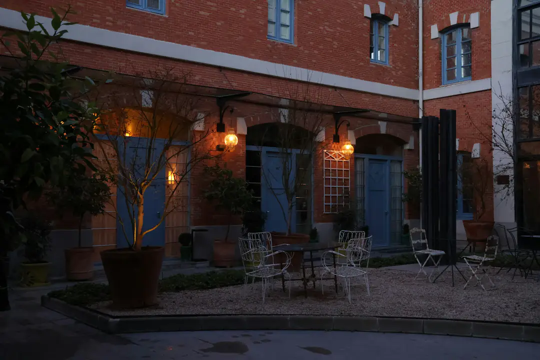 A quiet courtyard with tables under lit windows at dusk