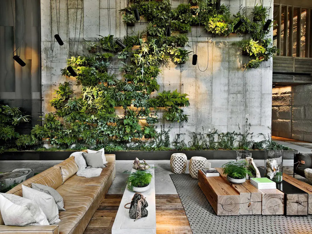 Lobby with a planted concrete wall, a leather sofa and coffee tables cut from thick timber beams