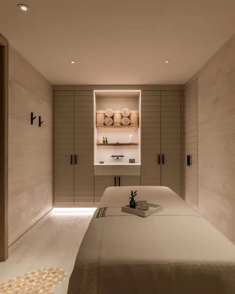 Bamford spa treatment room with pale timber walls, a massage table and a wooden heart on the wall