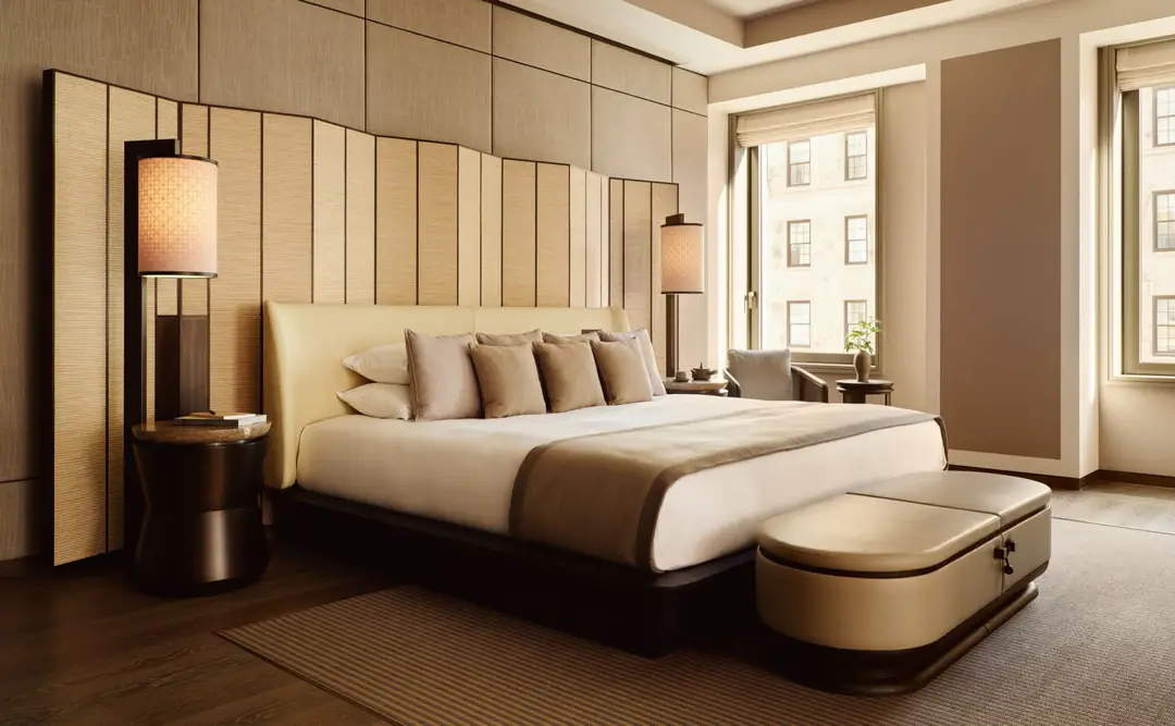 Corner Suite bedroom with a folding-screen headboard, two paper lamps and tall windows onto stone buildings