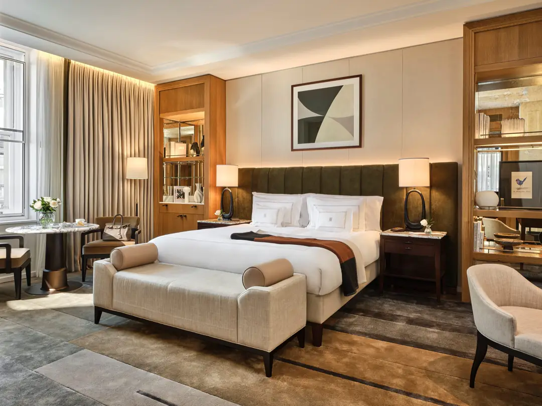 Trafalgar Suite bedroom: a king bed with white linen against a green velvet headboard, a linen bench at its foot