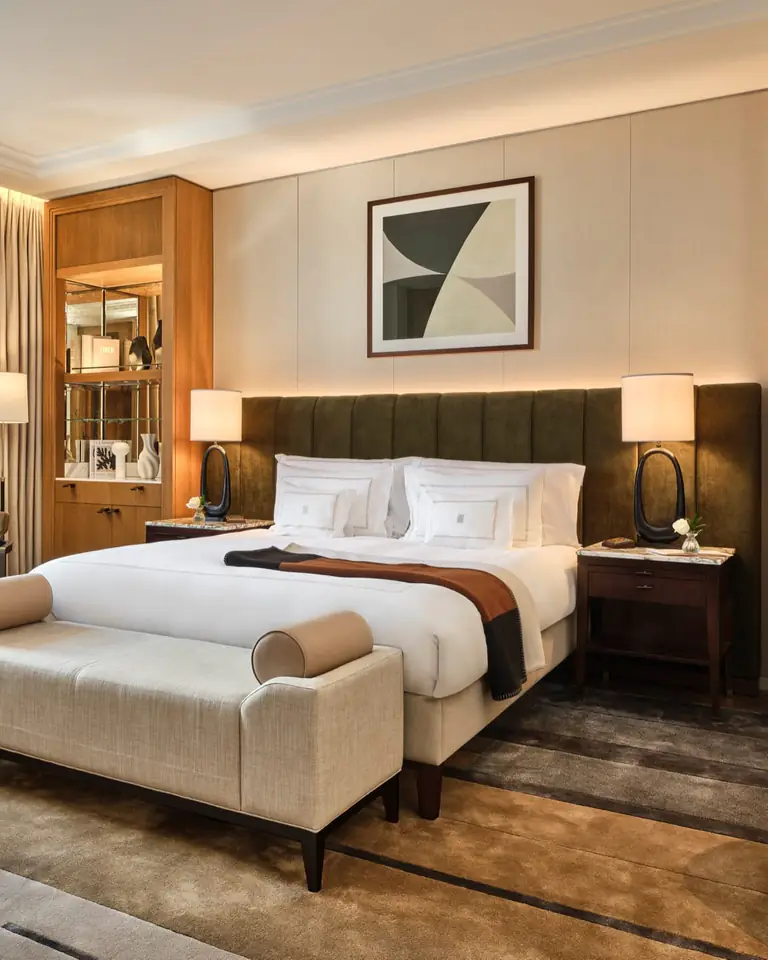 Trafalgar Suite bedroom: a king bed with white linen against a green velvet headboard, a linen bench at its foot