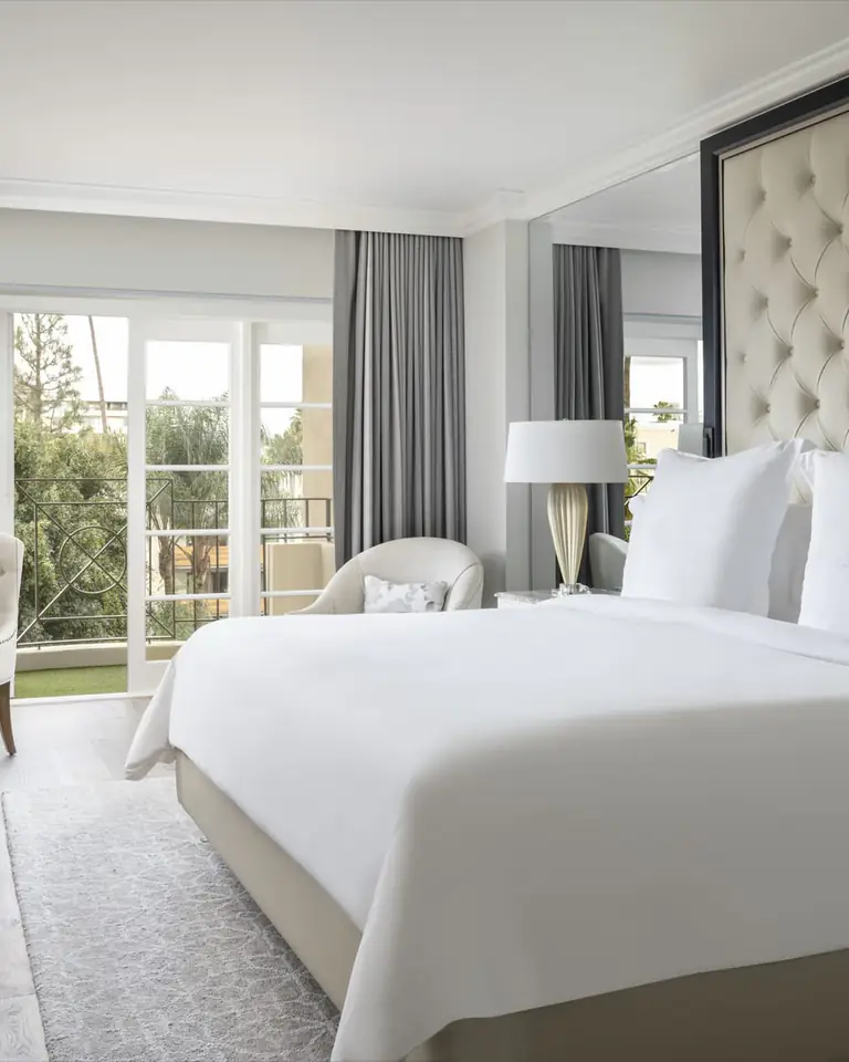 Wellness room with a tufted headboard, white bed, dumbbells and medicine ball, French doors open to a balcony