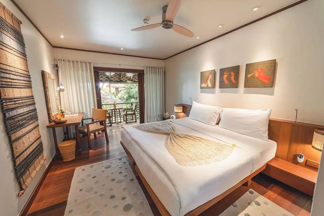 Hillside Room Garden View: white bed, wood floor, ceiling fan and open door to a balcony; no TV in view