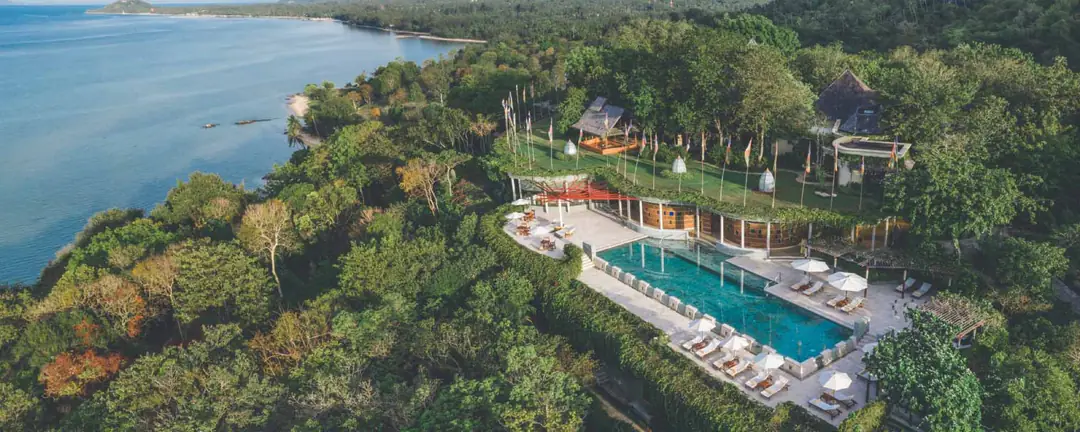 Aerial view of Kamalaya's lap pool and lawn on a forested headland above the sea