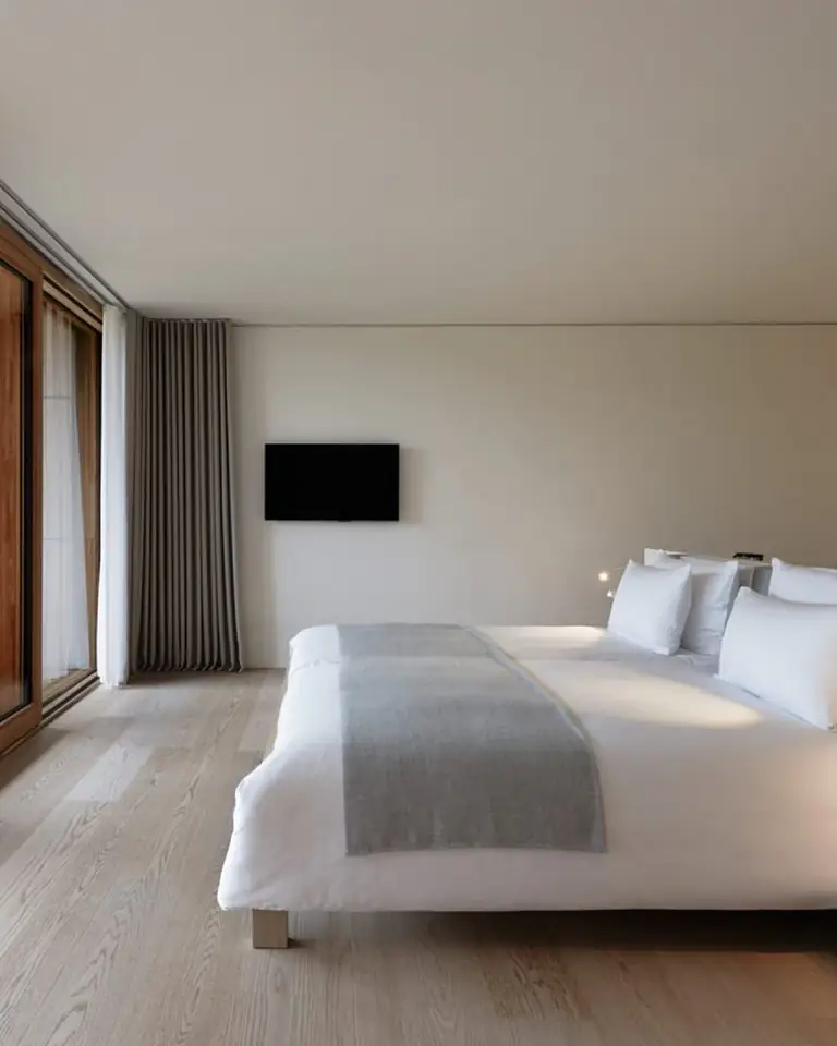 Double Room with a white bed, oak parquet and wood-framed glass doors open to a terrace