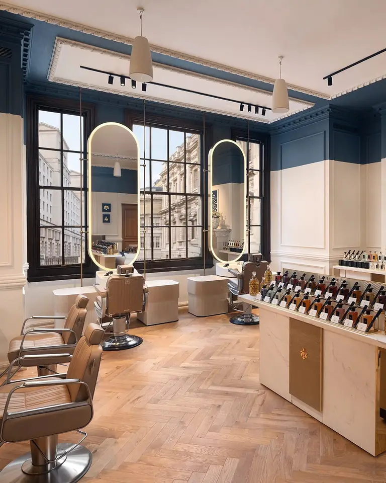 L'Atelier Guerlain salon with leather chairs, lit oval mirrors, herringbone floor and a perfume counter