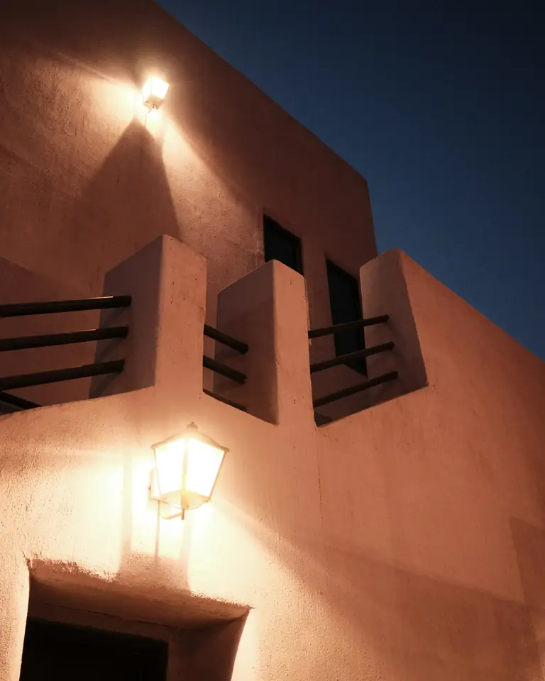 A stucco wall and doorway lit by a wall lamp at night