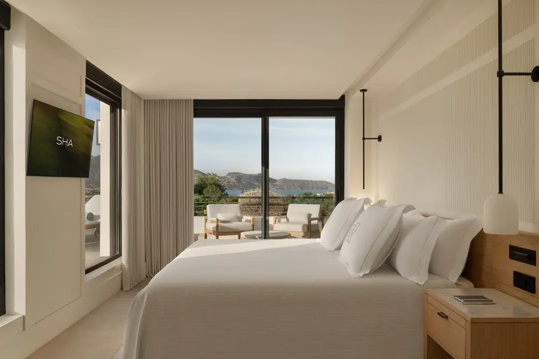 Presidential Suite bedroom with white bedding, oak headboard and a terrace looking over the bay