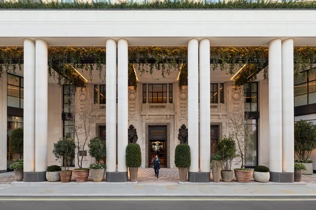The Whiteley's stone entrance behind tall white columns, with trailing plants and potted topiary at dusk