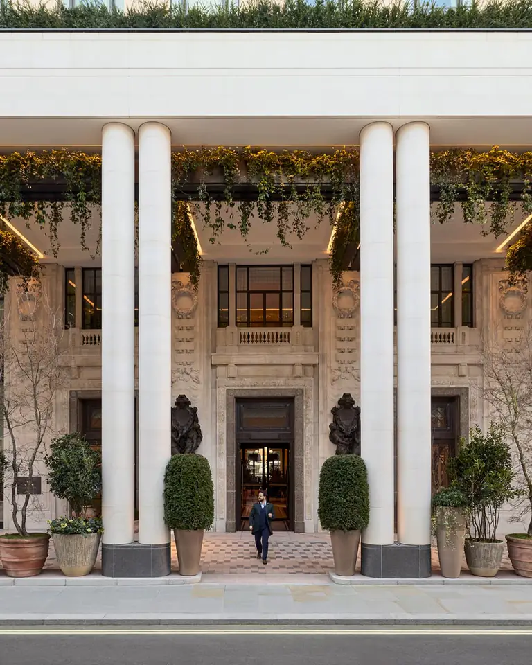 The Whiteley's stone entrance behind tall white columns, with trailing plants and potted topiary at dusk