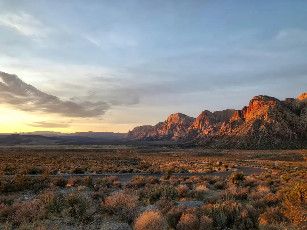 Rugged desert mountains and scrub under a soft sunset sky