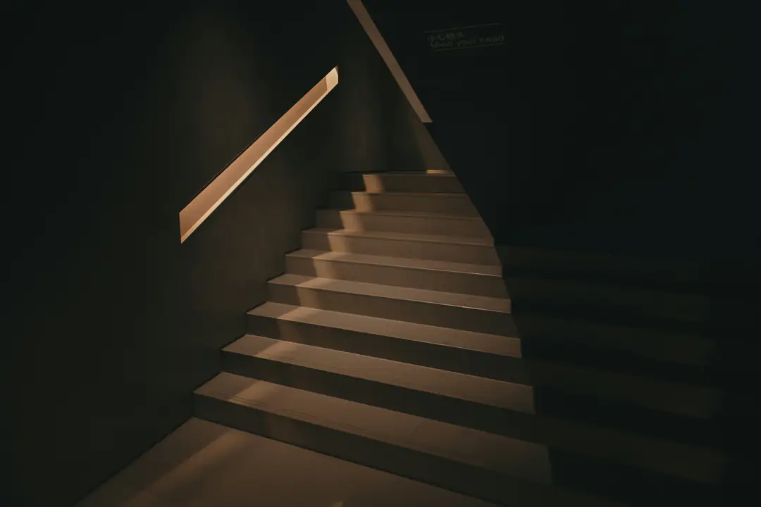 A dark stair crossed by a narrow beam of warm light